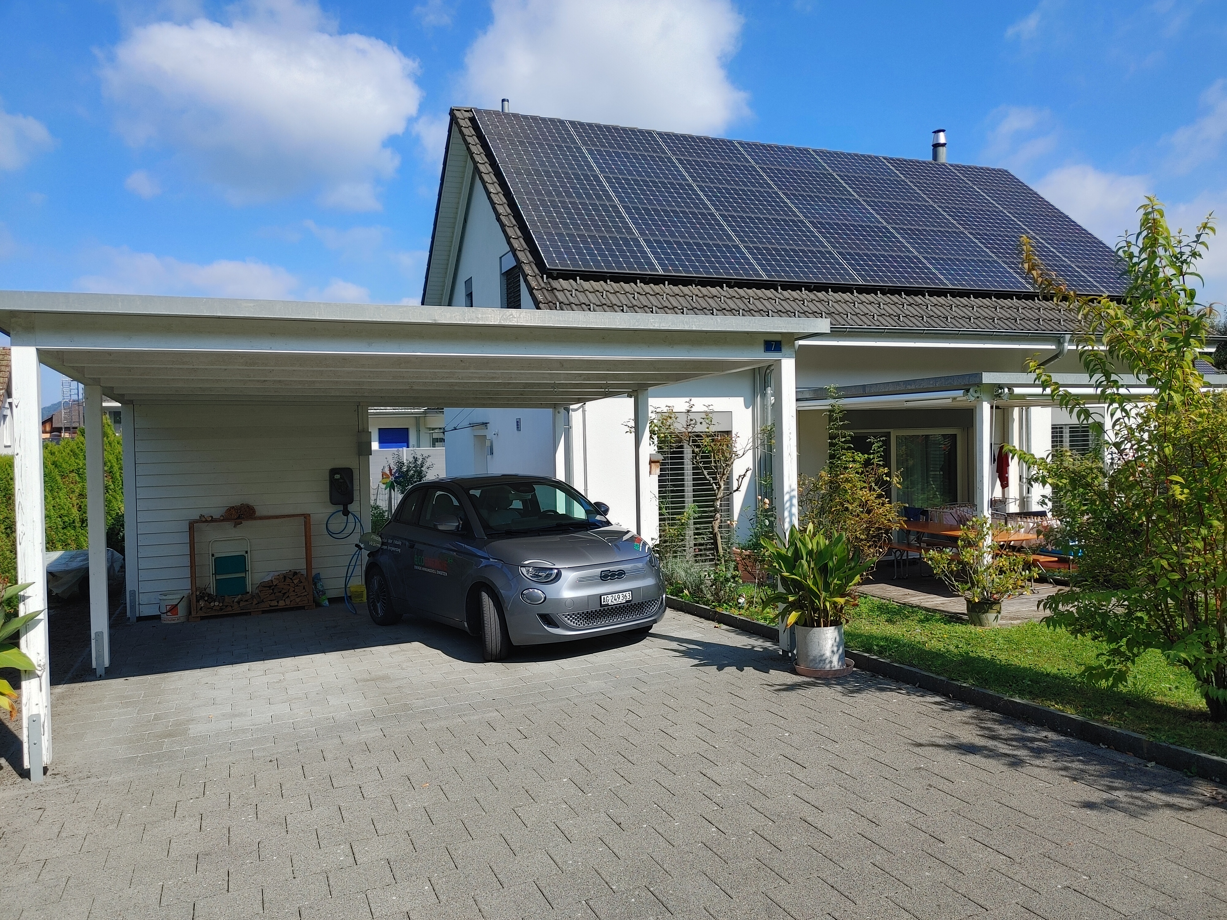 Haus mit Aufdach-PV-Anlage: E-Auto ist verbunden mit Ladestation und wird mit Solarstrom geladen | © eco energie a+ ag / Reto Karrer