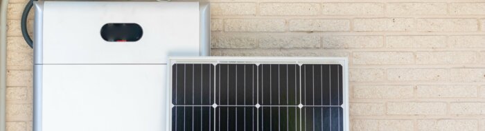Front view of photovoltaic panel and battery instalation leaning on the beige white wall with no people renewable energy | © NOWRA photography / Adobe Stock