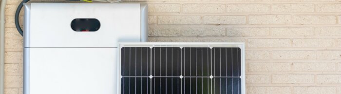 Front view of photovoltaic panel and battery instalation leaning on the beige white wall with no people renewable energy | © NOWRA photography / Adobe Stock