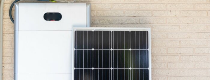 Front view of photovoltaic panel and battery instalation leaning on the beige white wall with no people renewable energy | © NOWRA photography / Adobe Stock