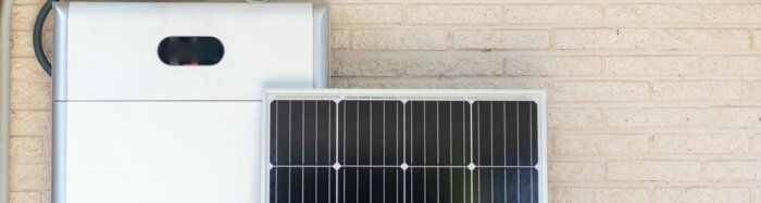 Front view of photovoltaic panel and battery instalation leaning on the beige white wall with no people renewable energy | © NOWRA photography / Adobe Stock