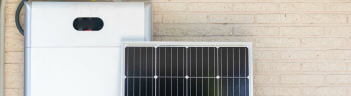 Front view of photovoltaic panel and battery instalation leaning on the beige white wall with no people renewable energy | © NOWRA photography / Adobe Stock