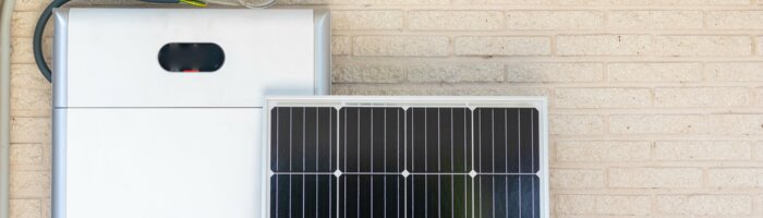 Front view of photovoltaic panel and battery instalation leaning on the beige white wall with no people renewable energy | © NOWRA photography / Adobe Stock