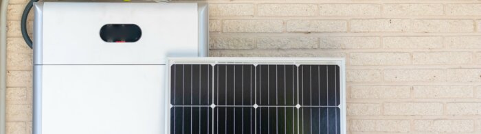 Front view of photovoltaic panel and battery instalation leaning on the beige white wall with no people renewable energy | © NOWRA photography / Adobe Stock