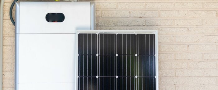 Front view of photovoltaic panel and battery instalation leaning on the beige white wall with no people renewable energy | © NOWRA photography / Adobe Stock