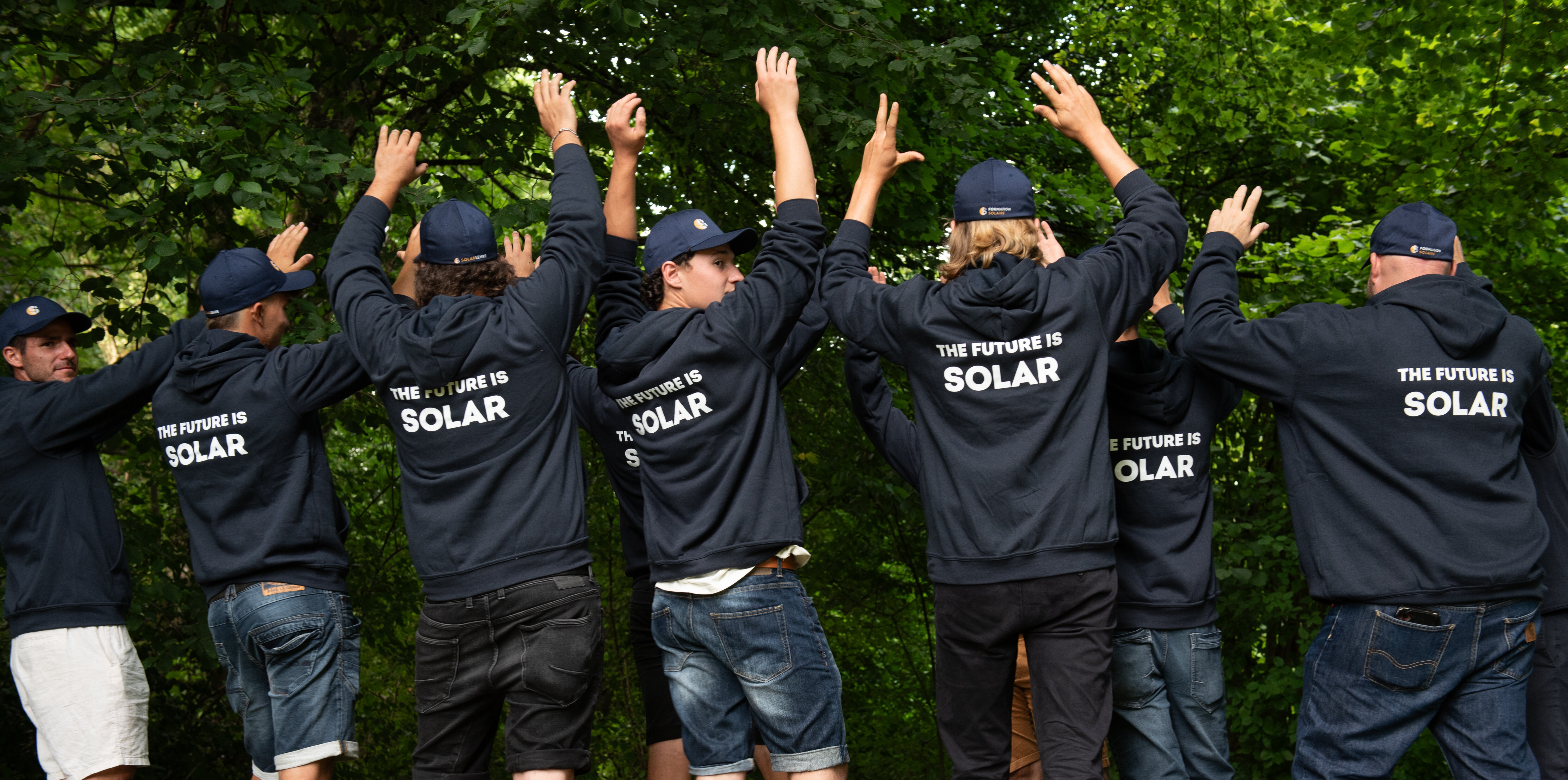 Solarinstallateure mit dunkelblauen Sweatshirts und Bäume im HIntergrund | © Swissolar / Céline Farias