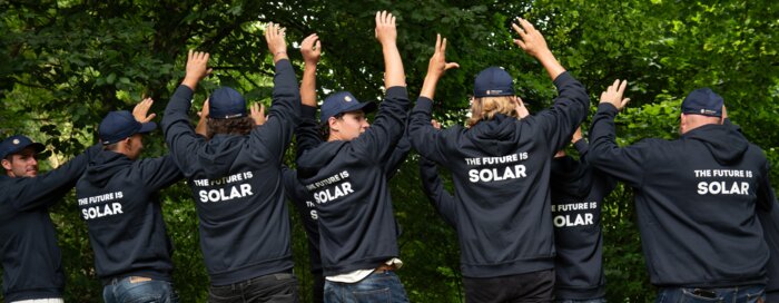 Solarinstallateure mit dunkelblauen Sweatshirts und Bäume im HIntergrund | © Swissolar / Céline Farias