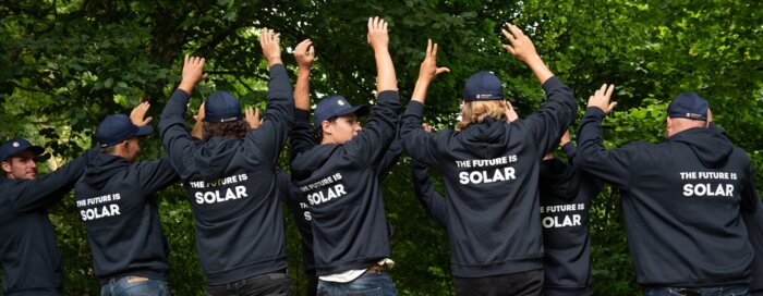 Solarinstallateure mit dunkelblauen Sweatshirts und Bäume im HIntergrund | © Swissolar / Céline Farias