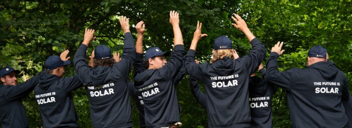 Solarinstallateure mit dunkelblauen Sweatshirts und Bäume im HIntergrund | © Swissolar / Céline Farias