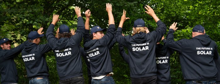 Solarinstallateure mit dunkelblauen Sweatshirts und Bäume im HIntergrund | © Swissolar / Céline Farias