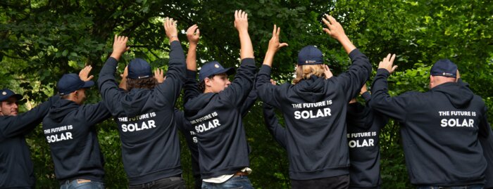 Solarinstallateure mit dunkelblauen Sweatshirts und Bäume im HIntergrund | © Swissolar / Céline Farias