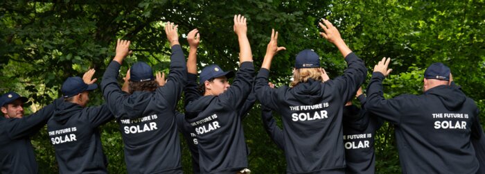 Solarinstallateure mit dunkelblauen Sweatshirts und Bäume im HIntergrund | © Swissolar / Céline Farias