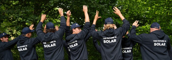 Solarinstallateure mit dunkelblauen Sweatshirts und Bäume im HIntergrund | © Swissolar / Céline Farias