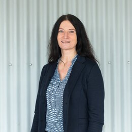 Frau mit schwarzem Jacket und gemusterter Bluse vor grauen Hintergrund | © Swissolar