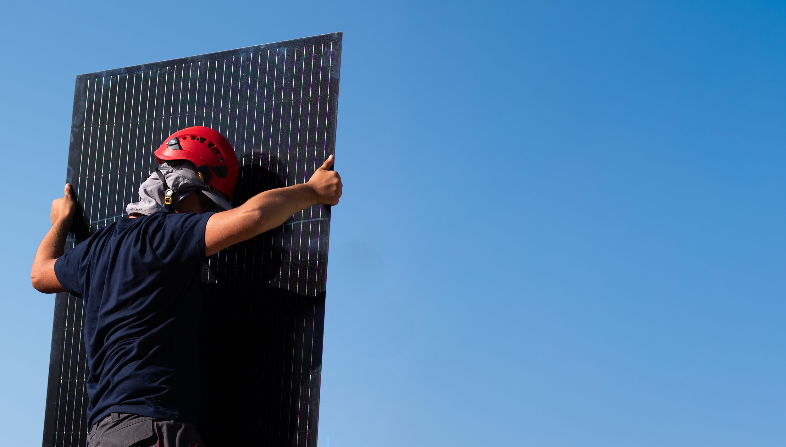 Mann mit schwarzen T-Shirt und PV-Panel vor blauen Hintergrund | © Swissolar / Cèline Farias